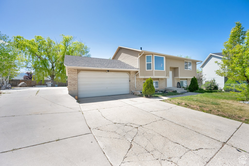 Split foyer home with an attached garage, driveway, and brick siding