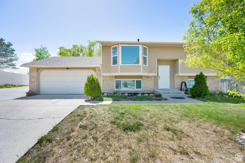 Split foyer home with brick siding, an attached garage, and concrete driveway