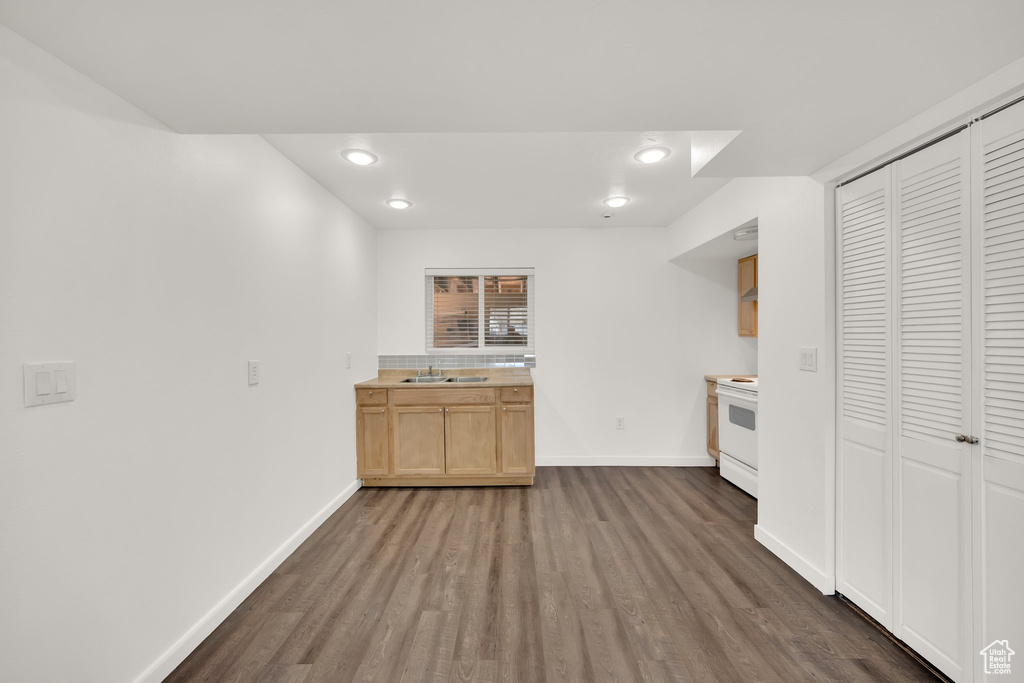 Kitchen featuring a sink, baseboards, dark wood-style flooring, light countertops, and white range with electric stovetop