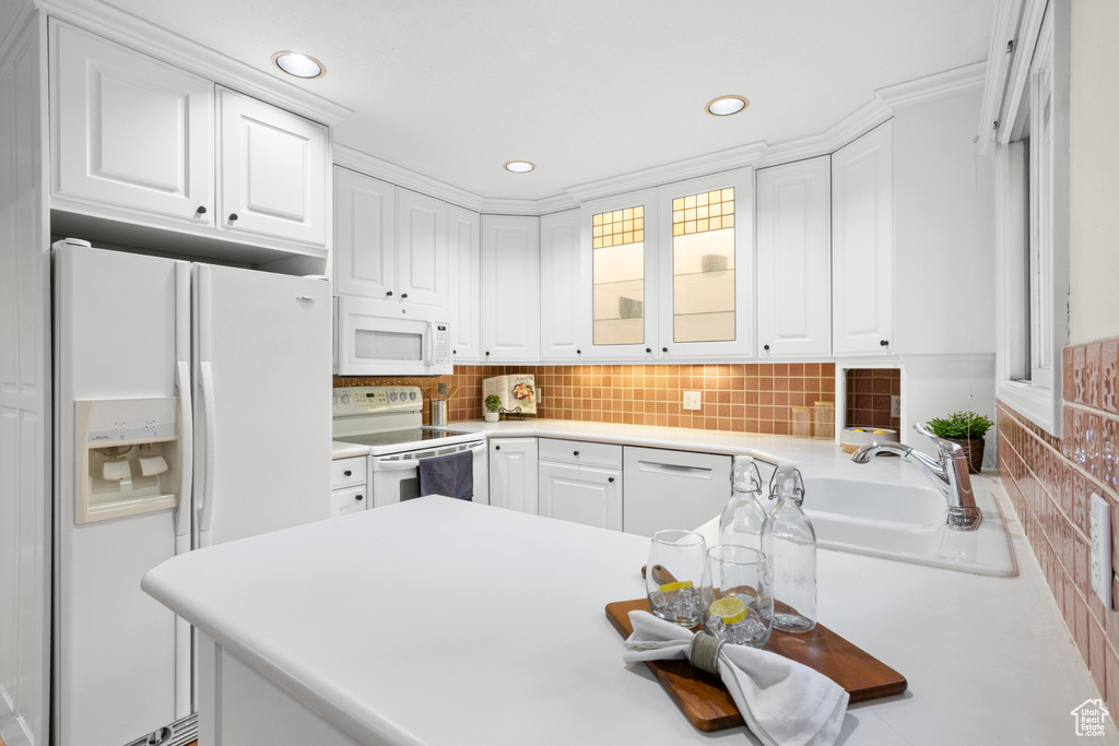 Kitchen with white appliances, white cabinetry, light countertops, decorative backsplash, and recessed lighting