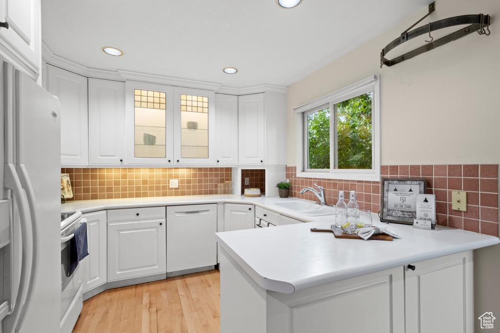 Kitchen featuring a sink, white appliances, white cabinetry, recessed lighting, and a peninsula