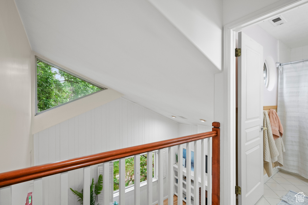 Corridor featuring vaulted ceiling and light tile patterned flooring