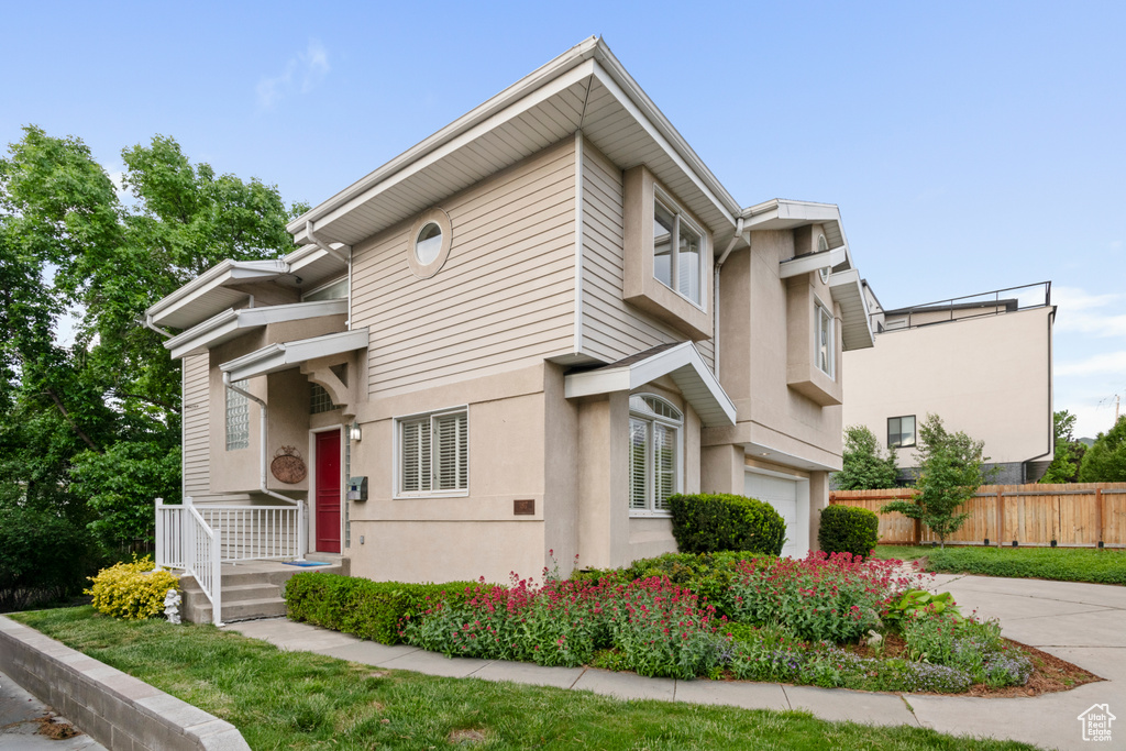 Multi unit property with a garage, fence, stucco siding, and concrete driveway