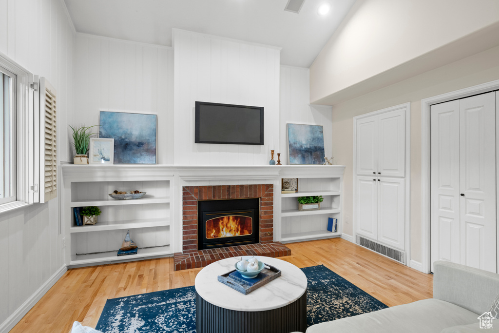 Living room with wood finished floors, a brick fireplace, and baseboards