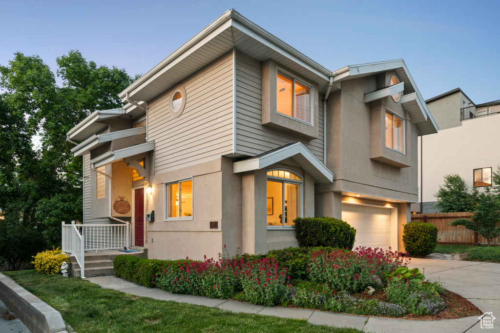 View of front of home with a garage, concrete driveway, stucco siding, and fence