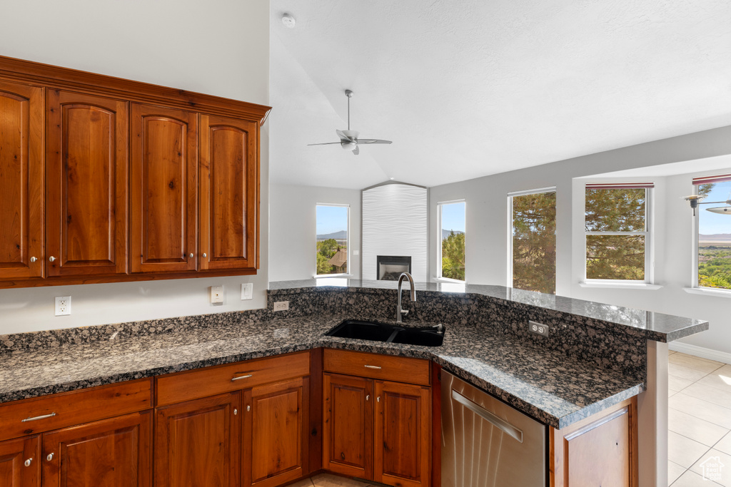 Kitchen featuring dishwasher, vaulted ceiling, a sink, light tile patterned flooring, and a ceiling fan