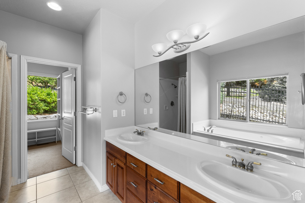 Full bath with plenty of natural light, tile patterned floors, double vanity, and a garden tub