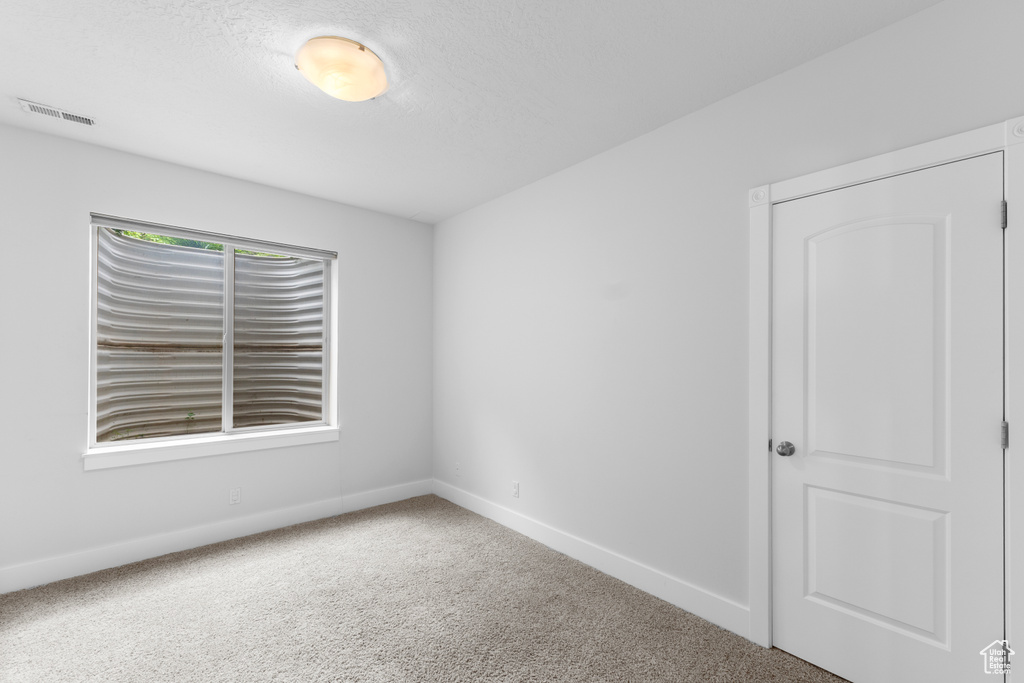 Unfurnished room featuring baseboards, carpet flooring, and a textured ceiling