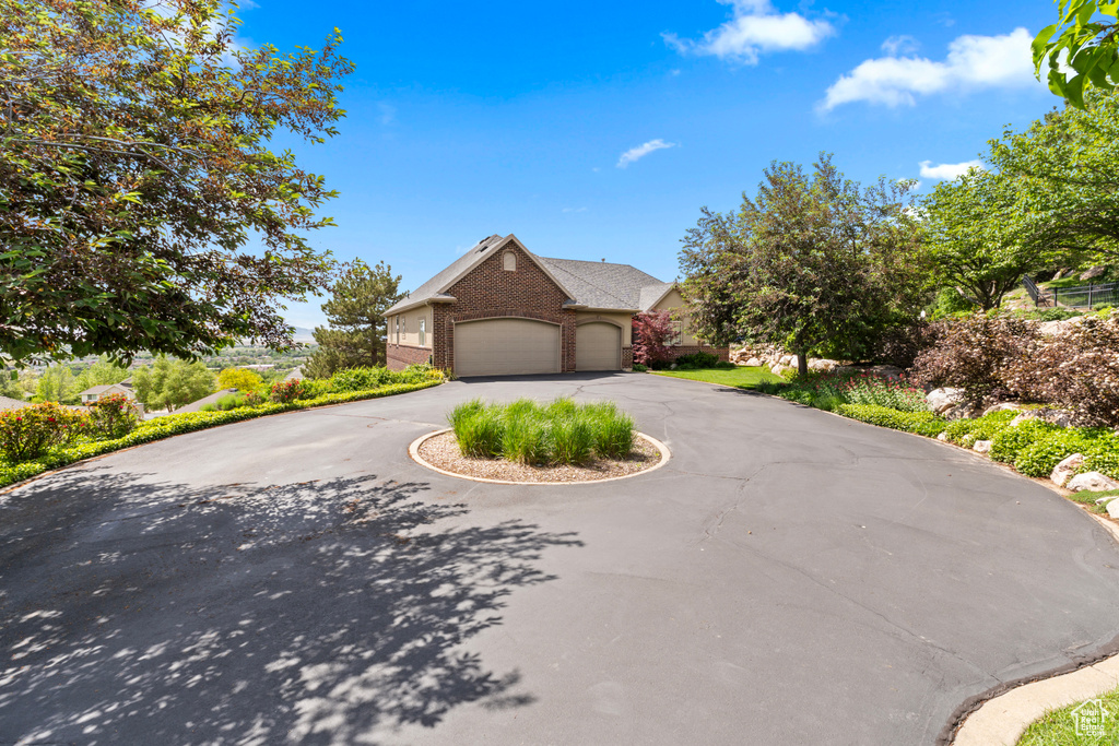 View of front of property with brick siding, curved driveway, and a garage
