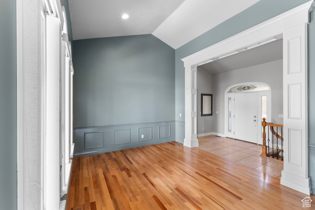 Entryway featuring decorative columns, light wood-style flooring, and lofted ceiling