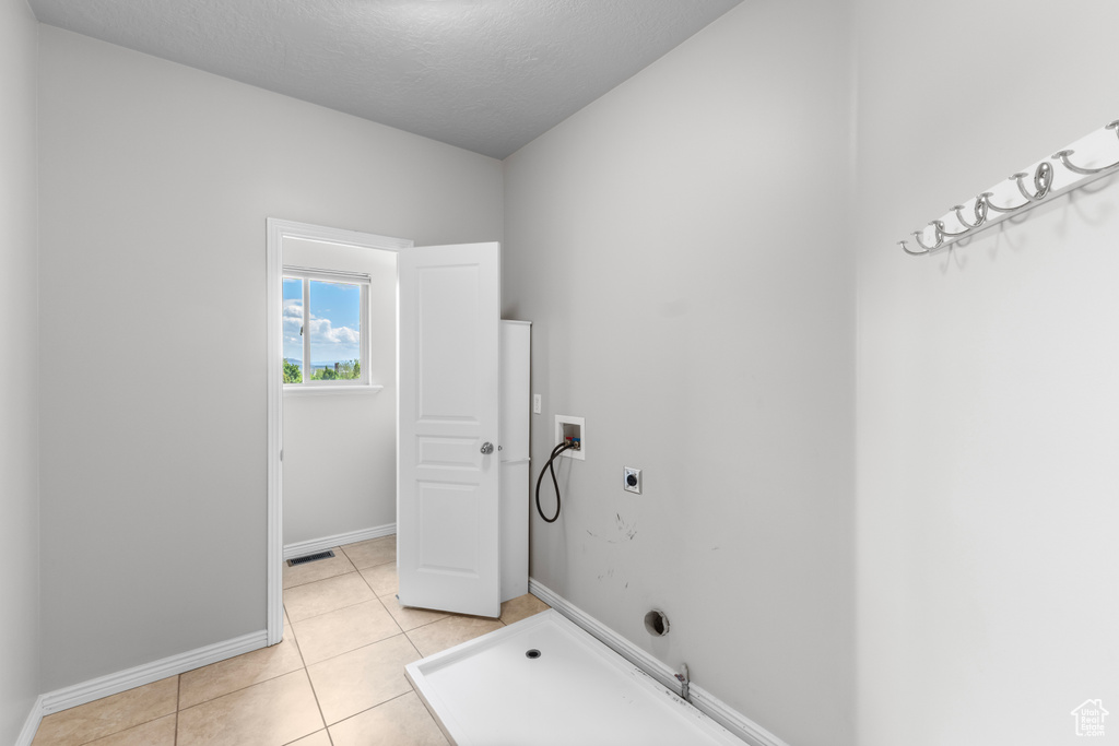 Clothes washing area featuring hookup for a washing machine, hookup for an electric dryer, light tile patterned flooring, baseboards, and gas dryer hookup