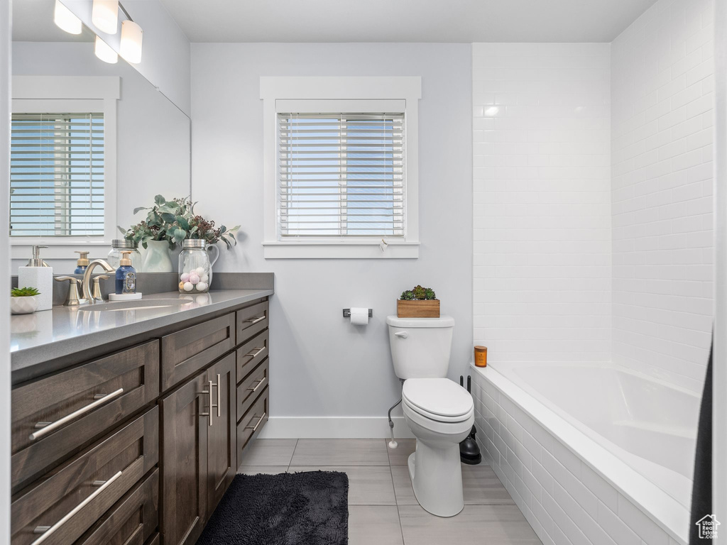 Bathroom featuring tile patterned floors, toilet, plenty of natural light, and vanity