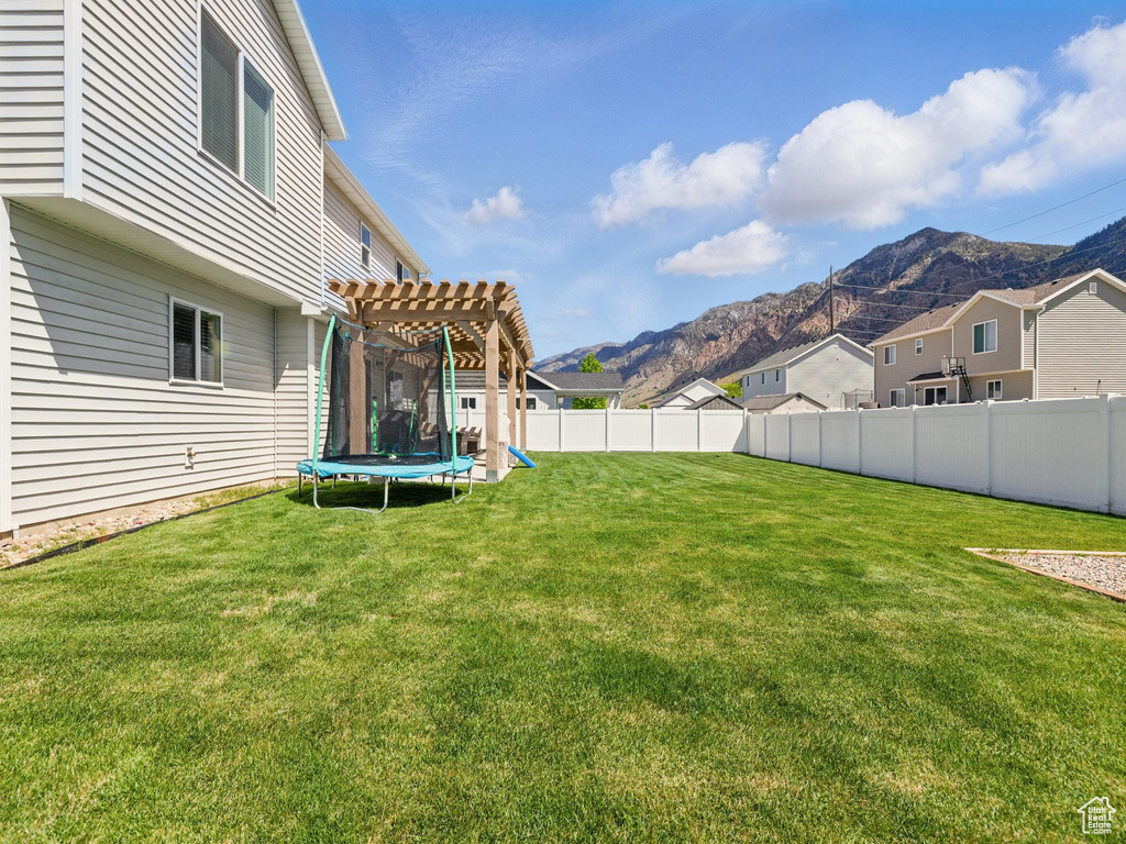 View of yard featuring a mountain view, a trampoline, a pergola, and a residential view