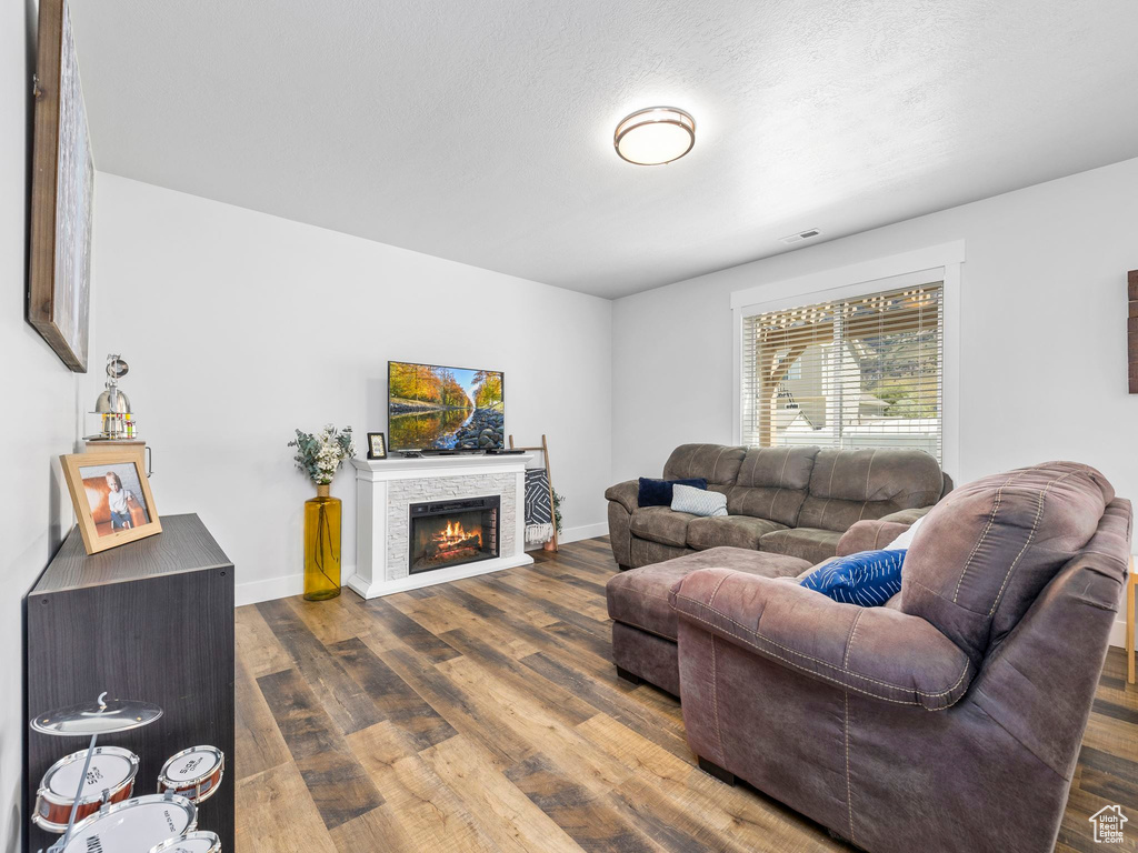 Living room with dark wood finished floors, a fireplace, and baseboards