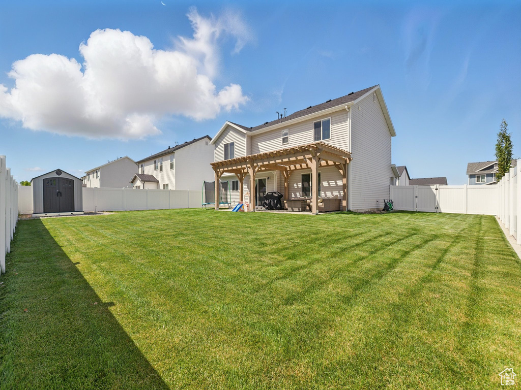 Back of house featuring a pergola, a storage unit, an outbuilding, and a patio area