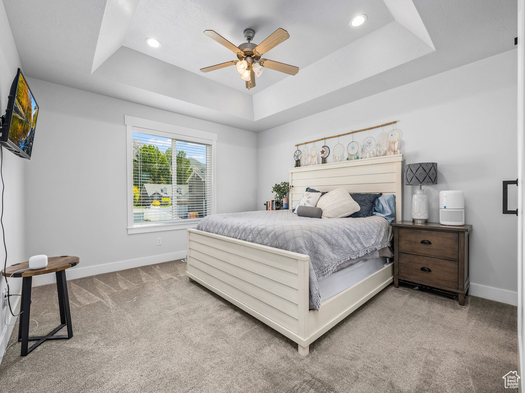 Bedroom with a raised ceiling, baseboards, carpet floors, recessed lighting, and a ceiling fan