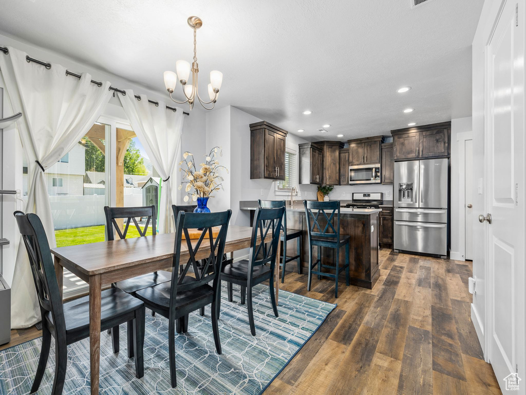 Dining room with plenty of natural light, a chandelier, dark wood-style flooring, and recessed lighting