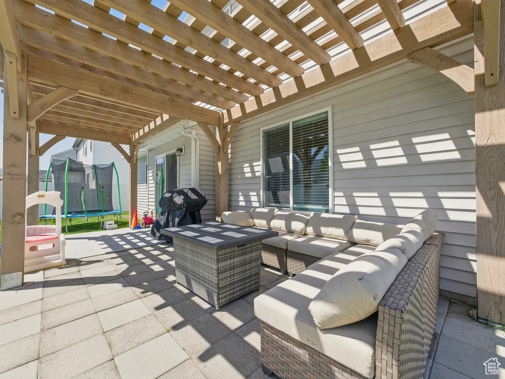 View of patio featuring a trampoline, outdoor lounge area, a pergola, and grilling area