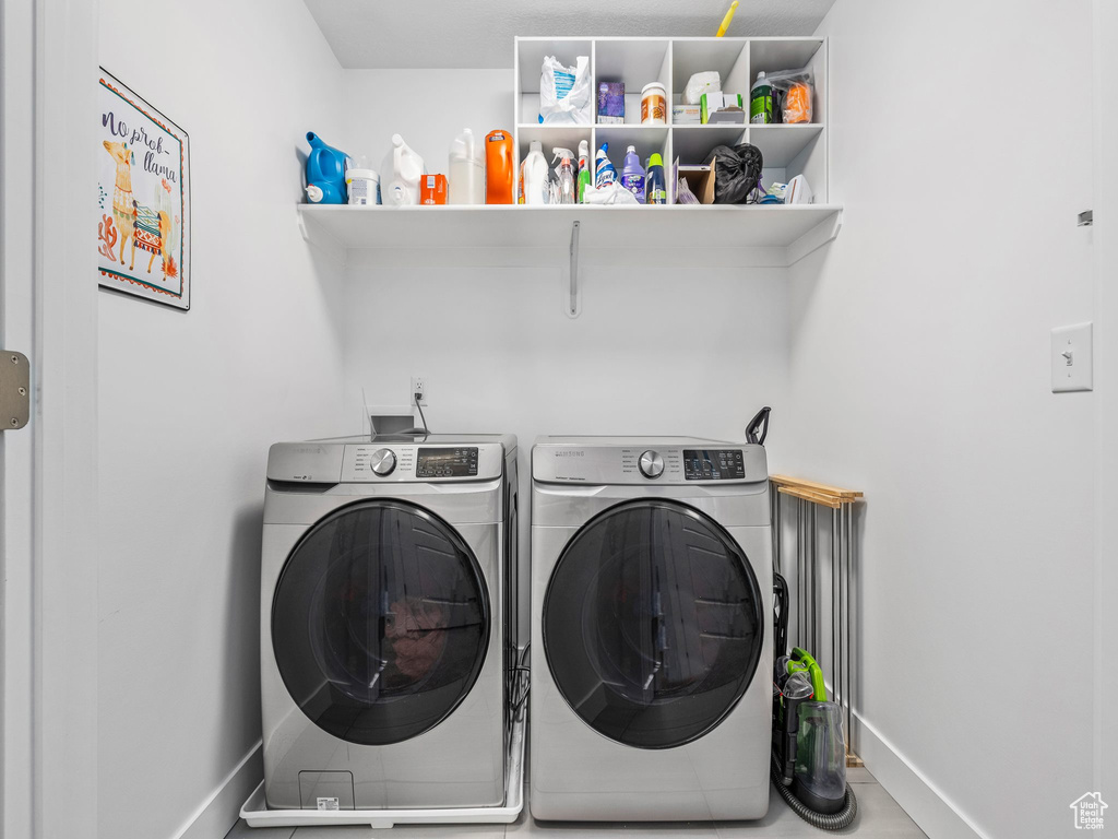 Clothes washing area featuring separate washer and dryer and baseboards