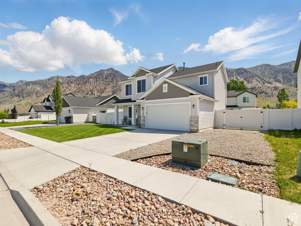 View of front of house featuring a mountain view, driveway, a gate, stone siding, and a garage