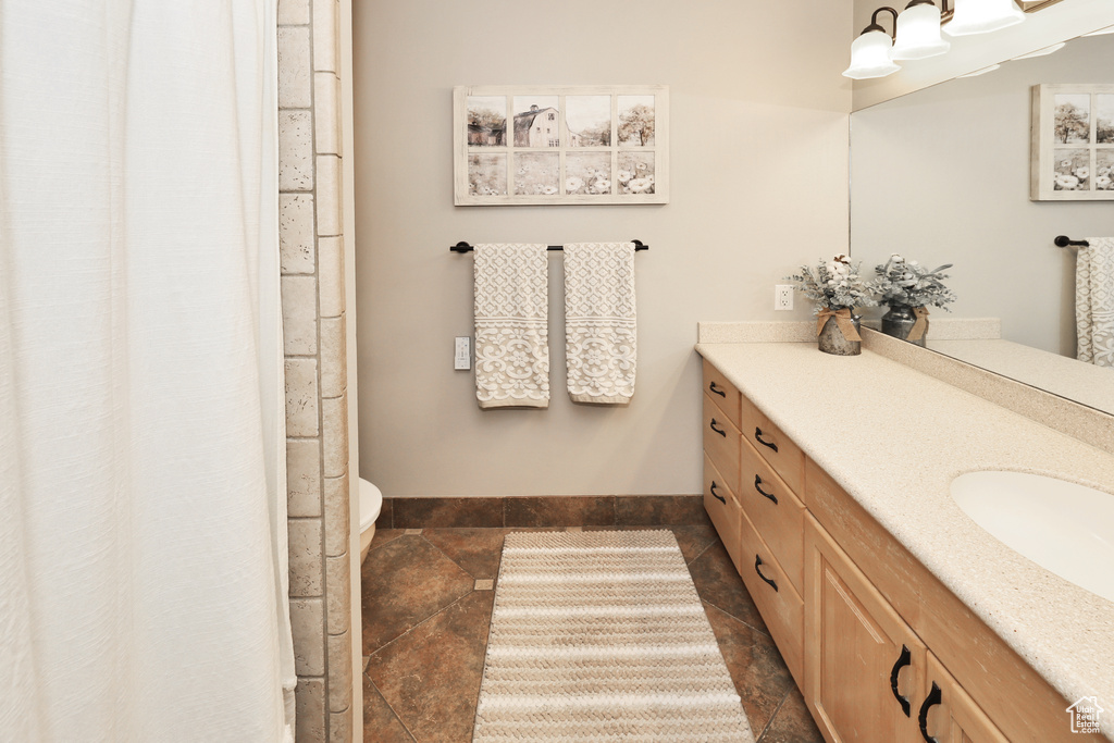 Bathroom with stone tile floors, vanity, baseboards, and toilet
