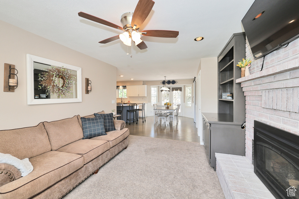 Living area with a ceiling fan, recessed lighting, a fireplace, and wood finished floors