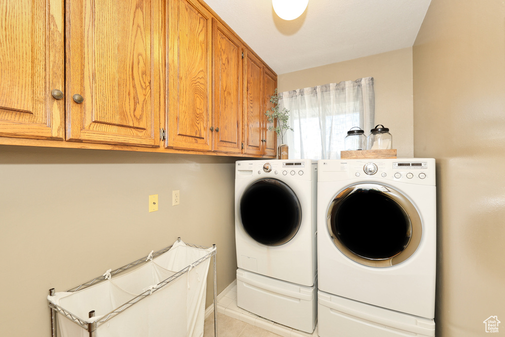 Washroom with washer and clothes dryer, cabinet space, and light tile patterned flooring