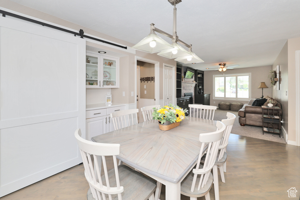 Dining area featuring ceiling fan, light wood-type flooring, a barn door, and baseboards
