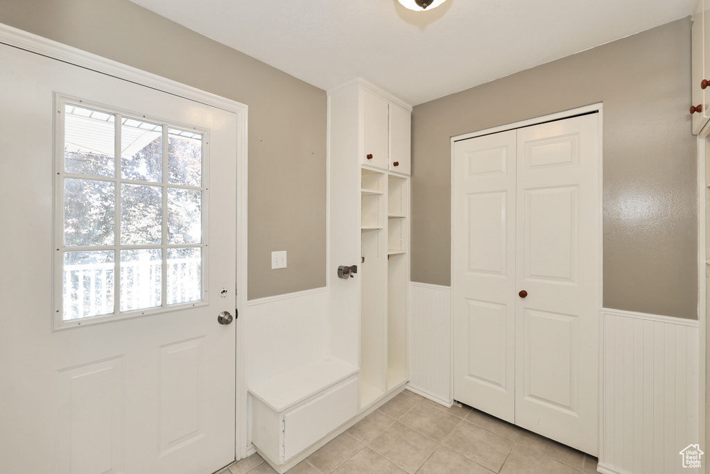 Mudroom with a wainscoted wall, healthy amount of natural light, and light tile patterned flooring