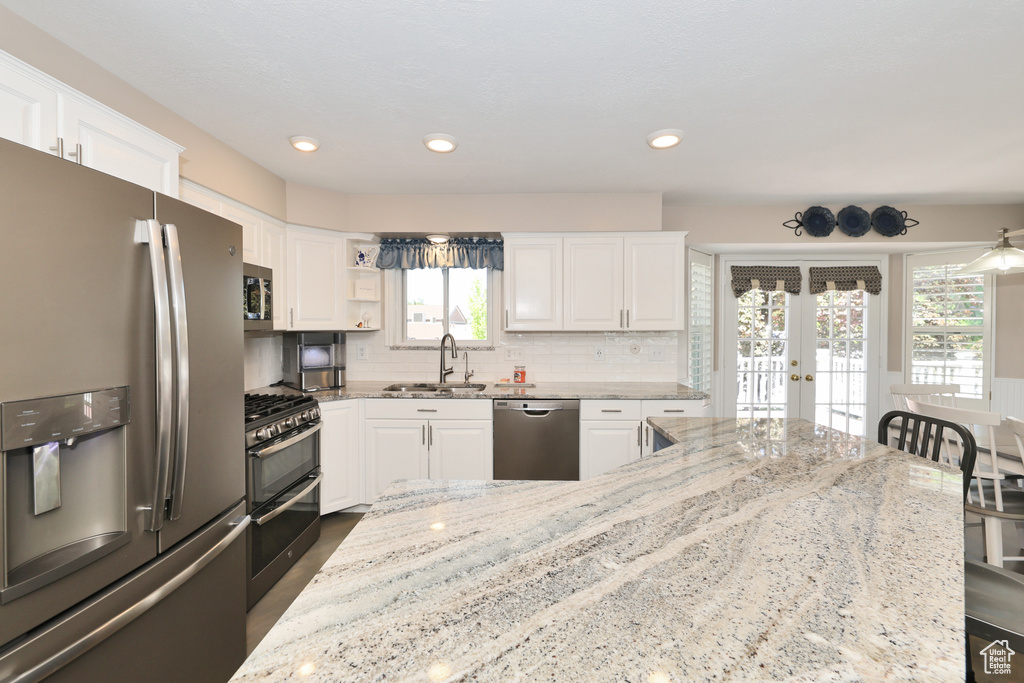 Kitchen featuring stainless steel appliances, a sink, french doors, white cabinetry, and recessed lighting