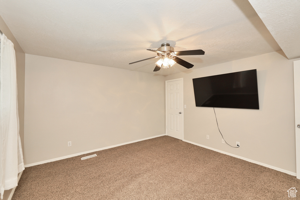 Empty room featuring carpet flooring, ceiling fan, and baseboards