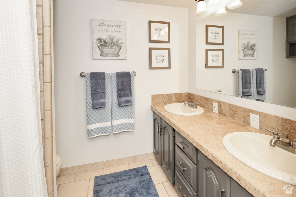 Bathroom featuring double vanity, tile patterned flooring, toilet, and a shower with curtain