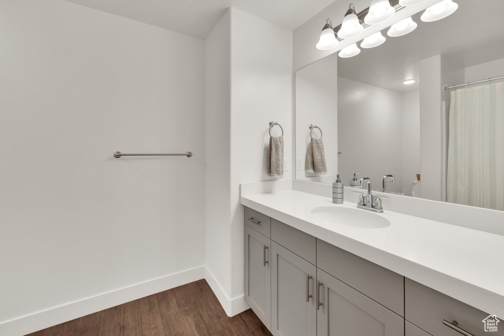 Full bath with wood finished floors, vanity, and baseboards