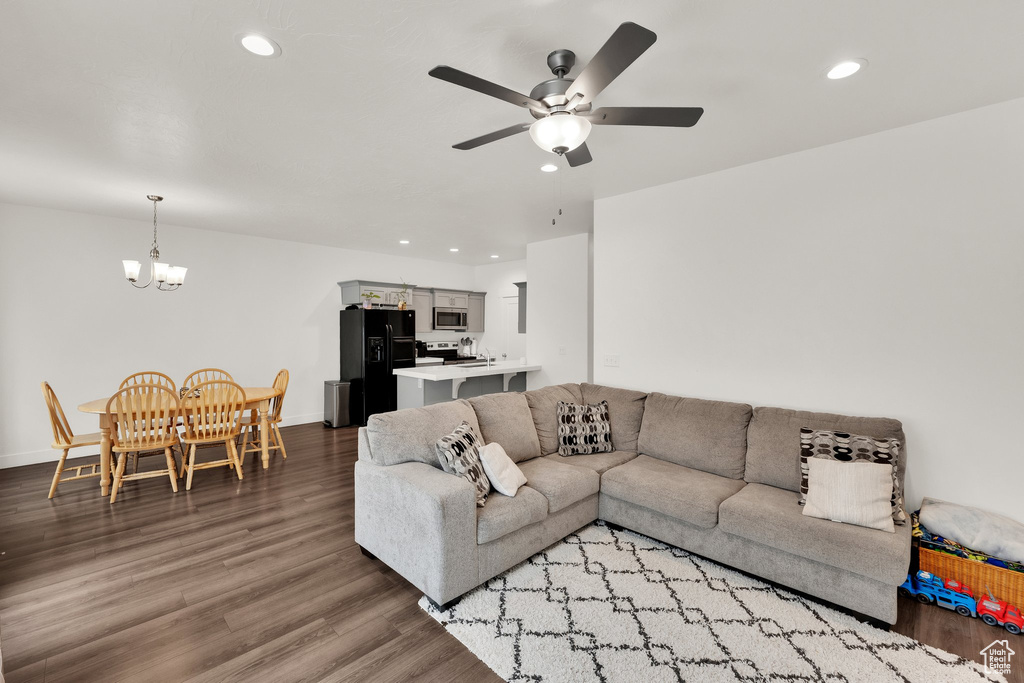 Living area featuring a chandelier, a ceiling fan, recessed lighting, wood finished floors, and baseboards