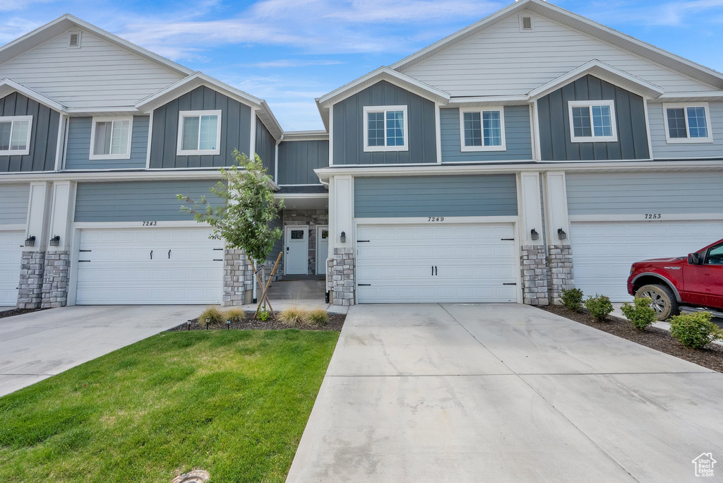 View of front of property with board and batten siding, stone siding, an attached garage, and driveway