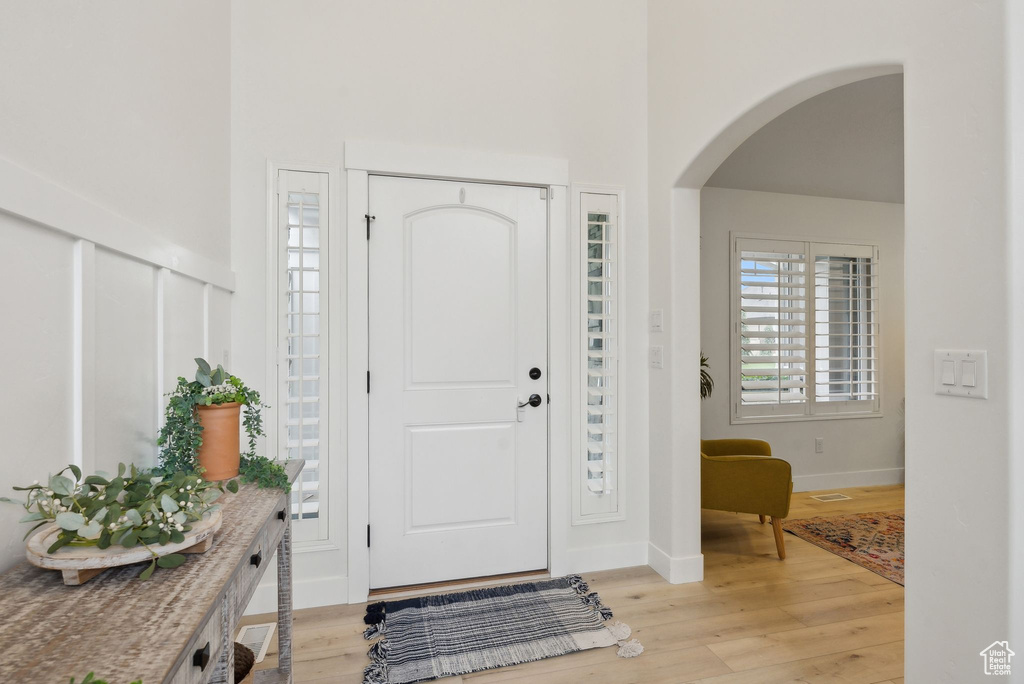 Entryway with arched walkways, a high ceiling, light wood finished floors, and baseboards