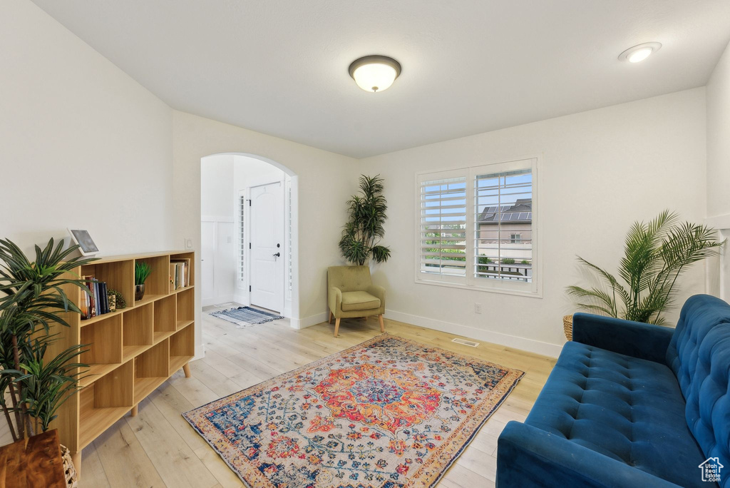 Living area with arched walkways, light wood-style flooring, and baseboards