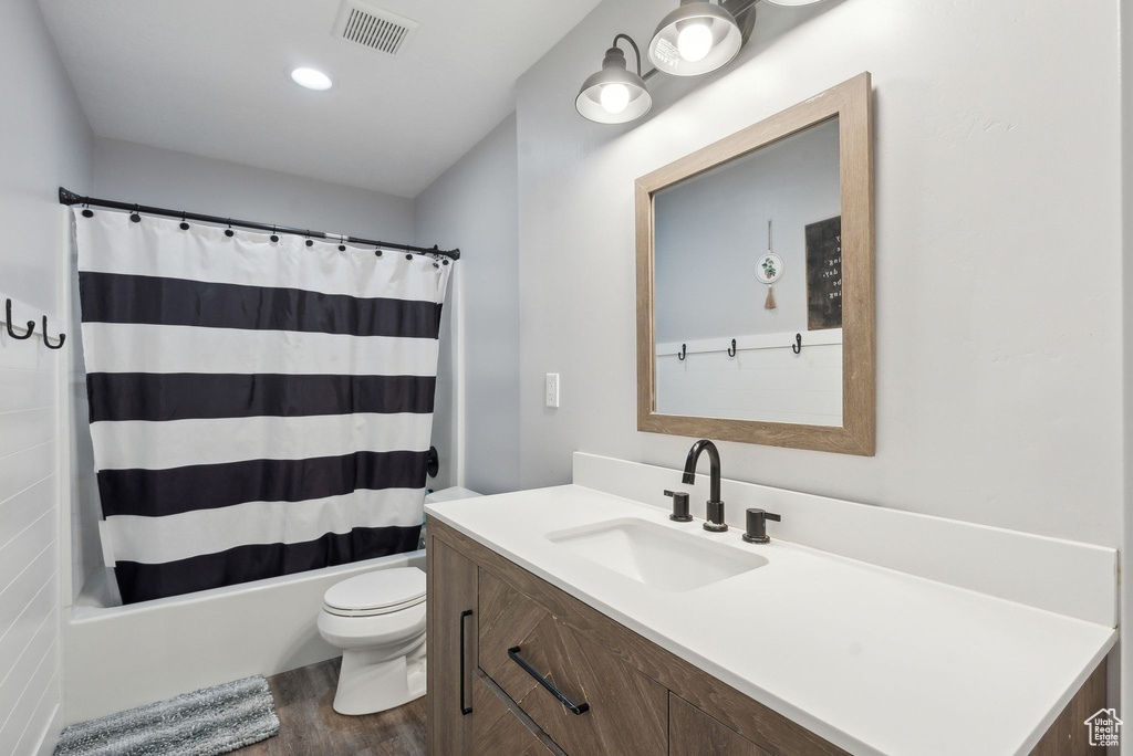 Full bath with wood finished floors, toilet, shower / bath combo, and vanity