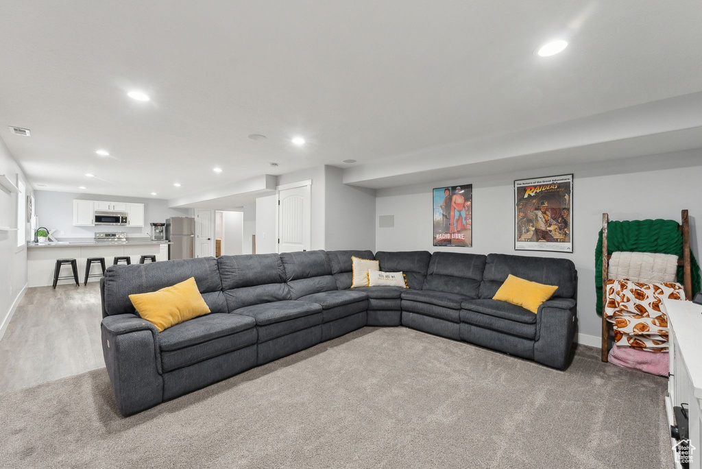 Living area featuring recessed lighting, light carpet, baseboards, and light wood-type flooring