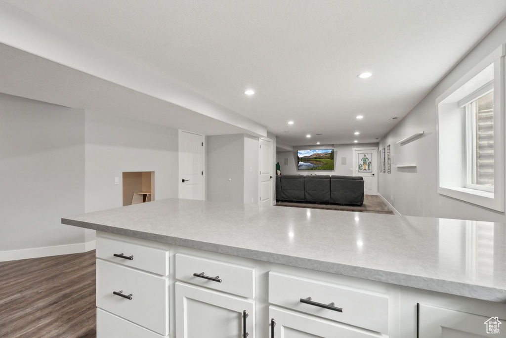 Kitchen with recessed lighting, light countertops, dark wood-type flooring, white cabinets, and baseboards