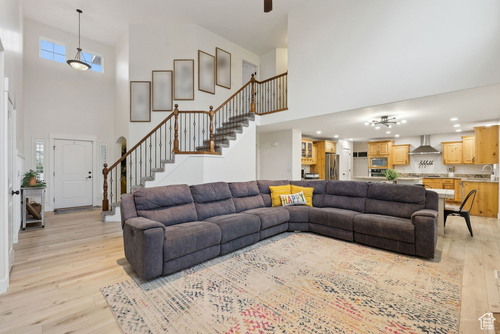 Living room with a towering ceiling, stairway, light wood-style flooring, recessed lighting, and a ceiling fan