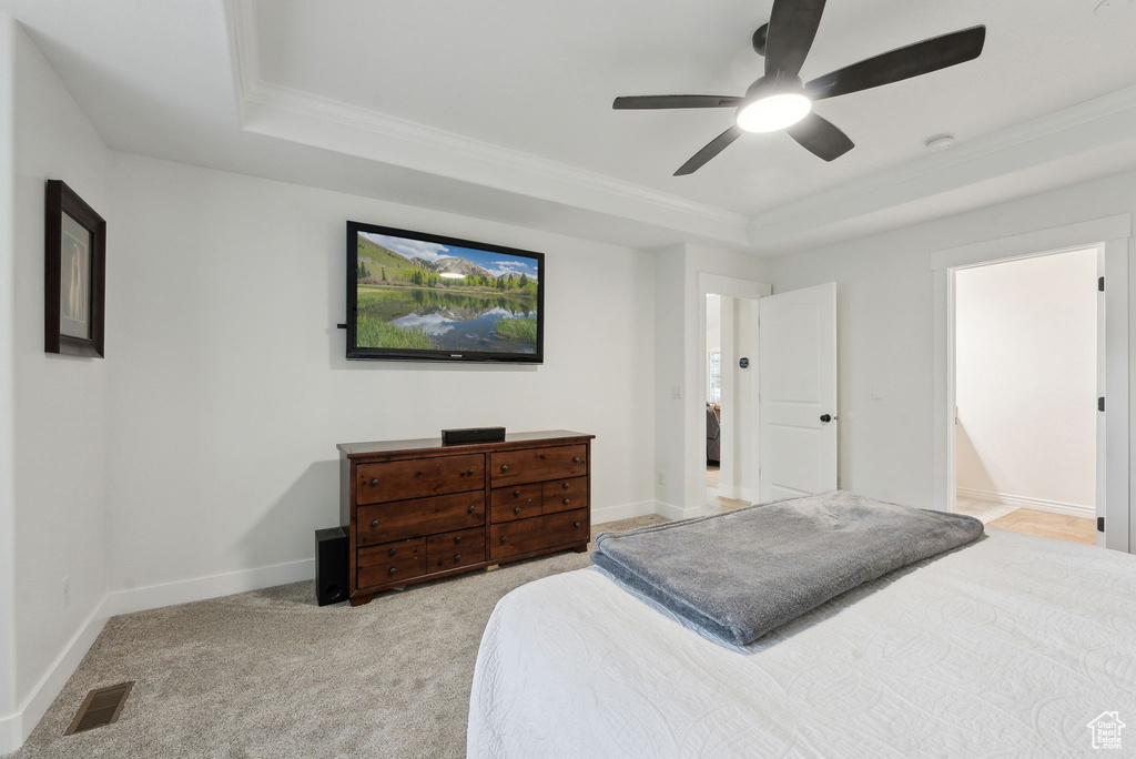 Bedroom featuring a raised ceiling, ornamental molding, light carpet, a ceiling fan, and baseboards