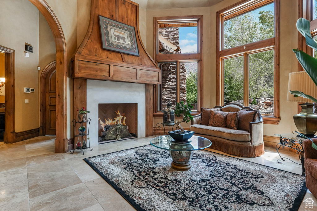 Living area with a towering ceiling, arched walkways, and a lit fireplace