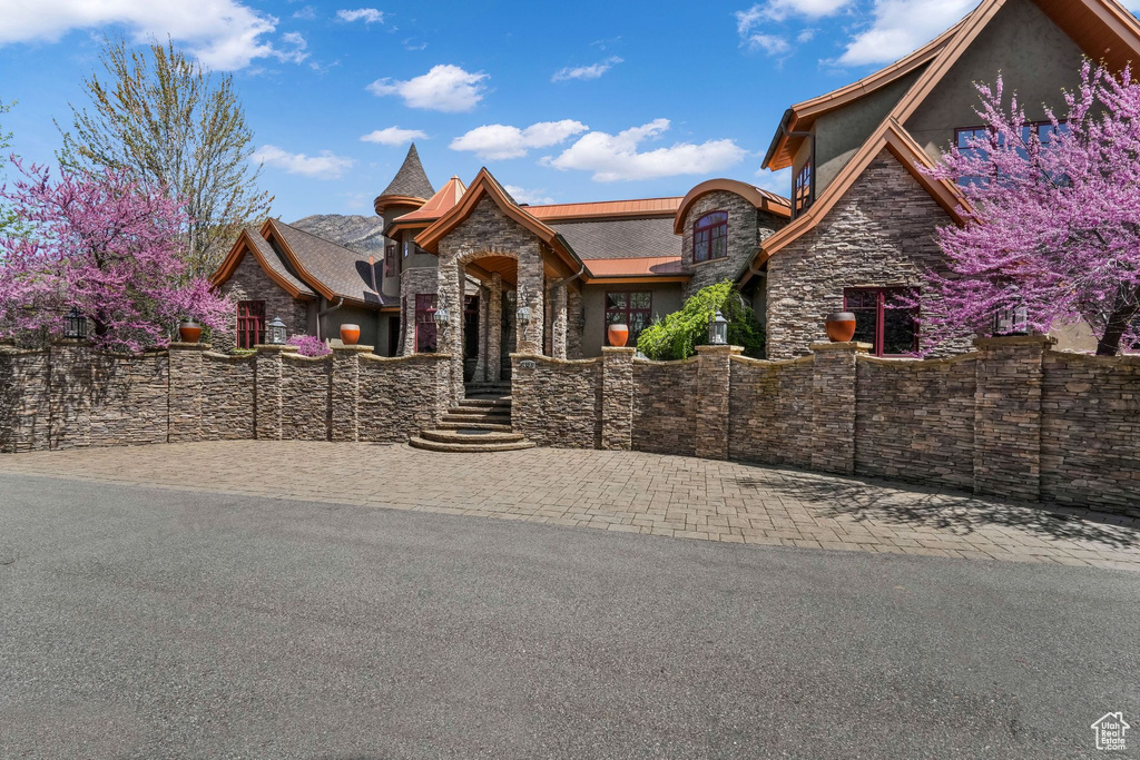 View of front of property featuring stone siding, stucco siding, and fence