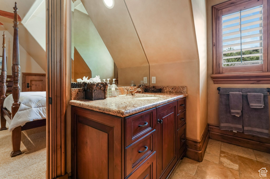 Bathroom with stone tile floors, vanity, connected bathroom, and baseboards
