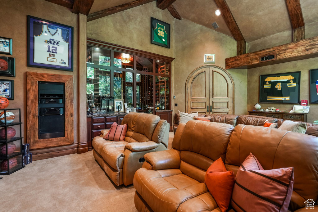Cinema room featuring beam ceiling, high vaulted ceiling, light colored carpet, and bar