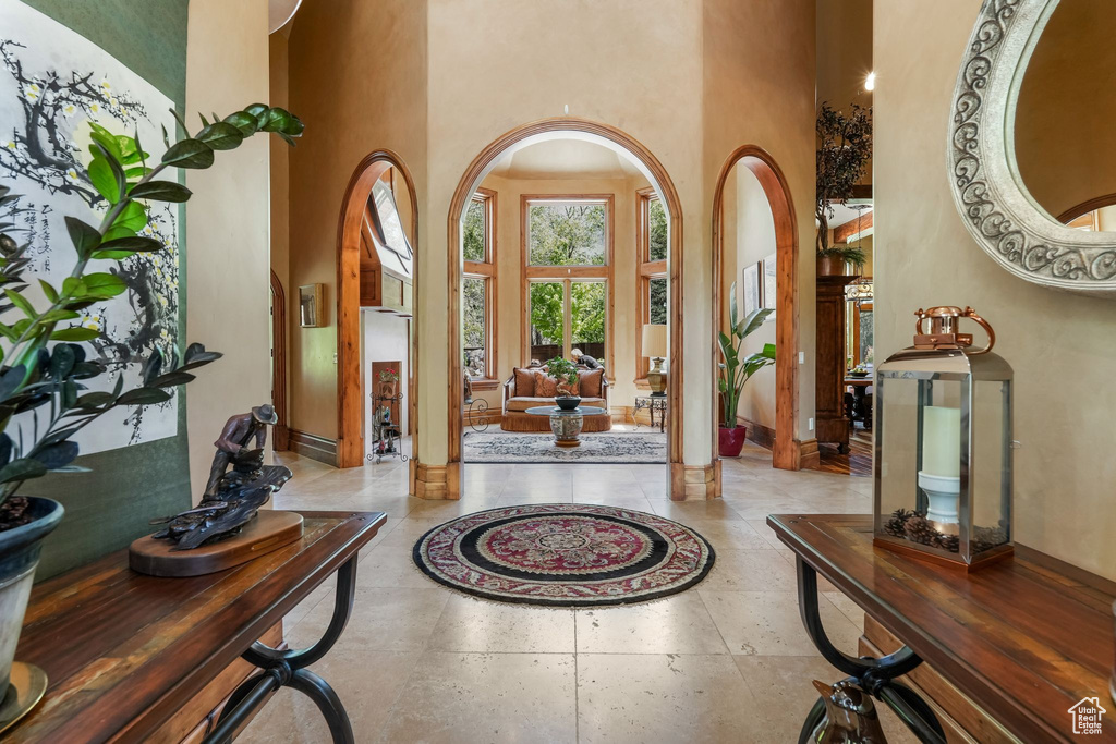 Foyer featuring a towering ceiling, arched walkways, baseboards, and ornate columns