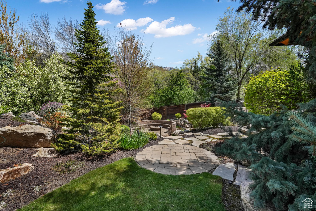 View of yard with an outdoor fire pit, fence, a patio, and a wooded view