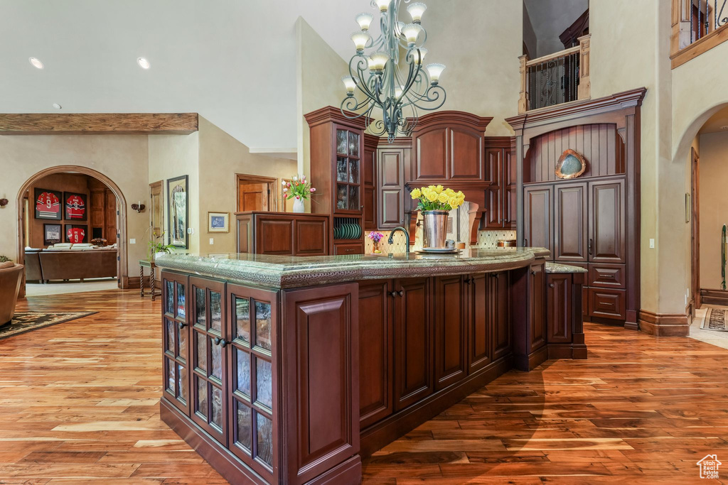 Bar area with arched walkways, a high ceiling, light wood-style floors, baseboards, and a chandelier