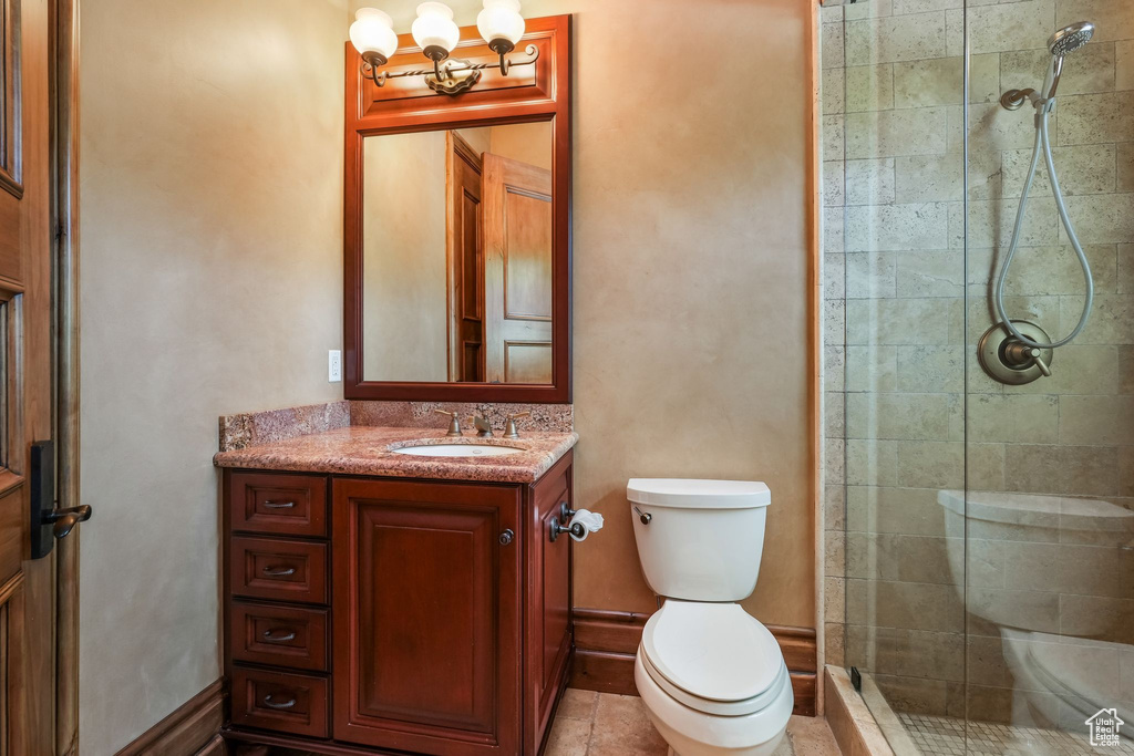 Full bath with toilet, a tile shower, vanity, and a chandelier